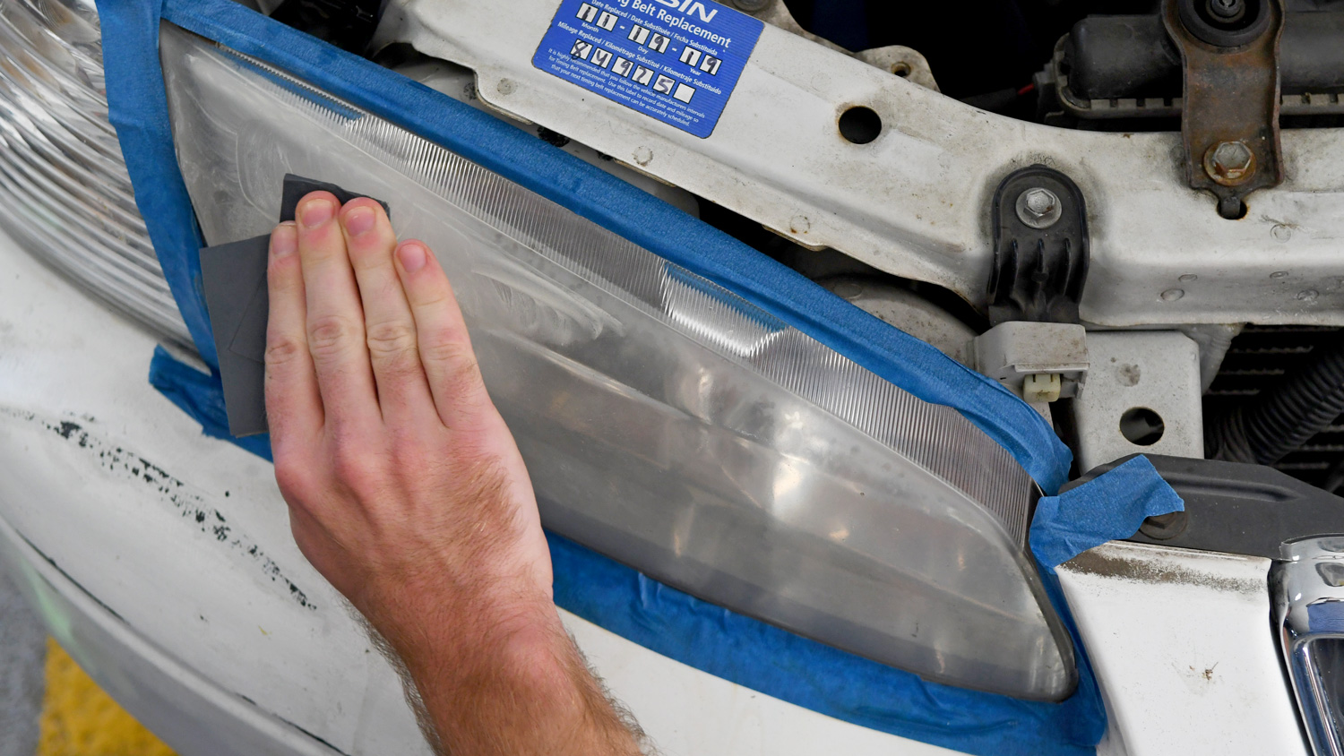 The Sylvania Headlight Restoration Kit being used to clean a vehicle headlight.