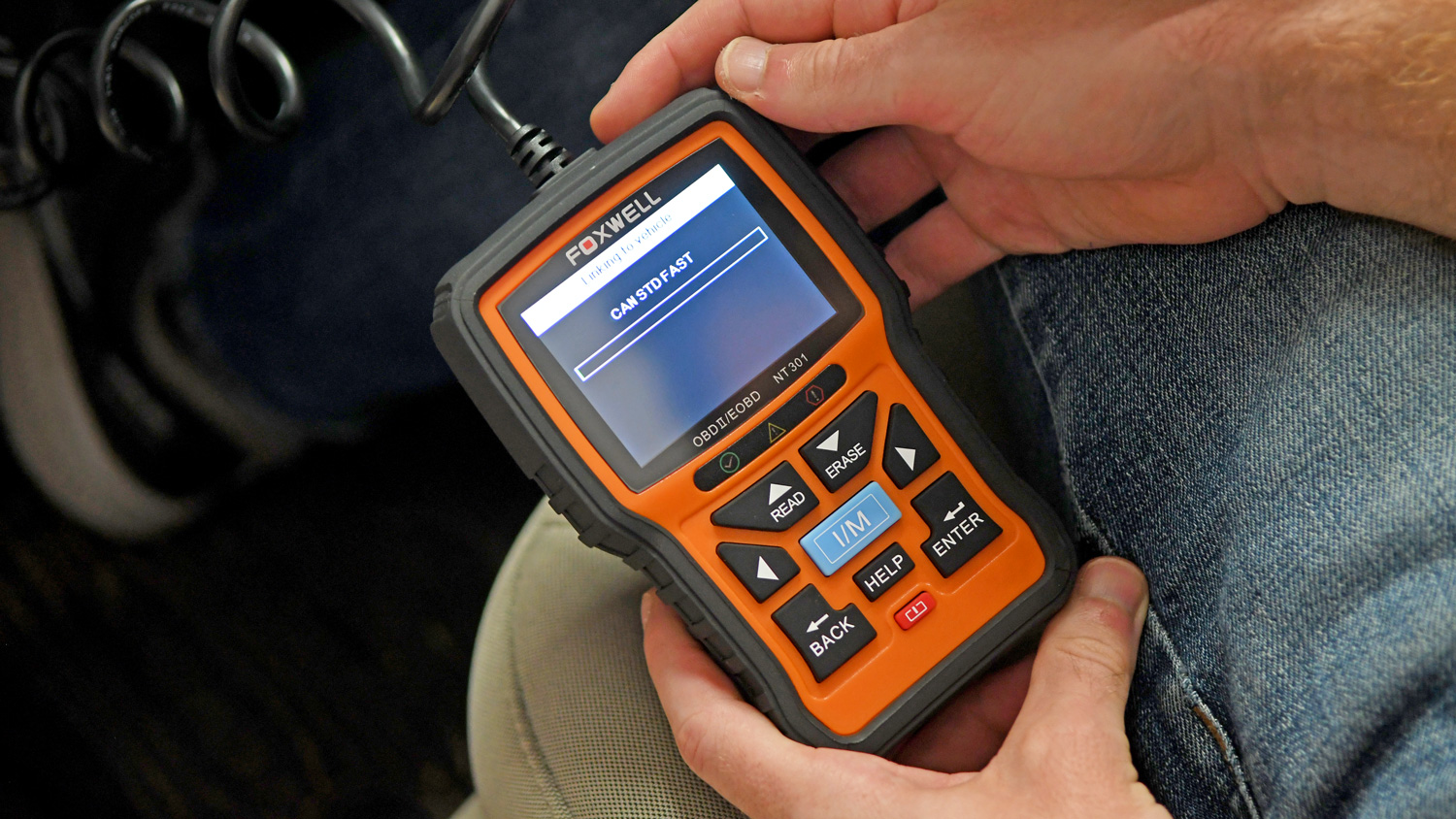 The Foxwell NT301 OBD2 Scanner being installed into a vehicle.