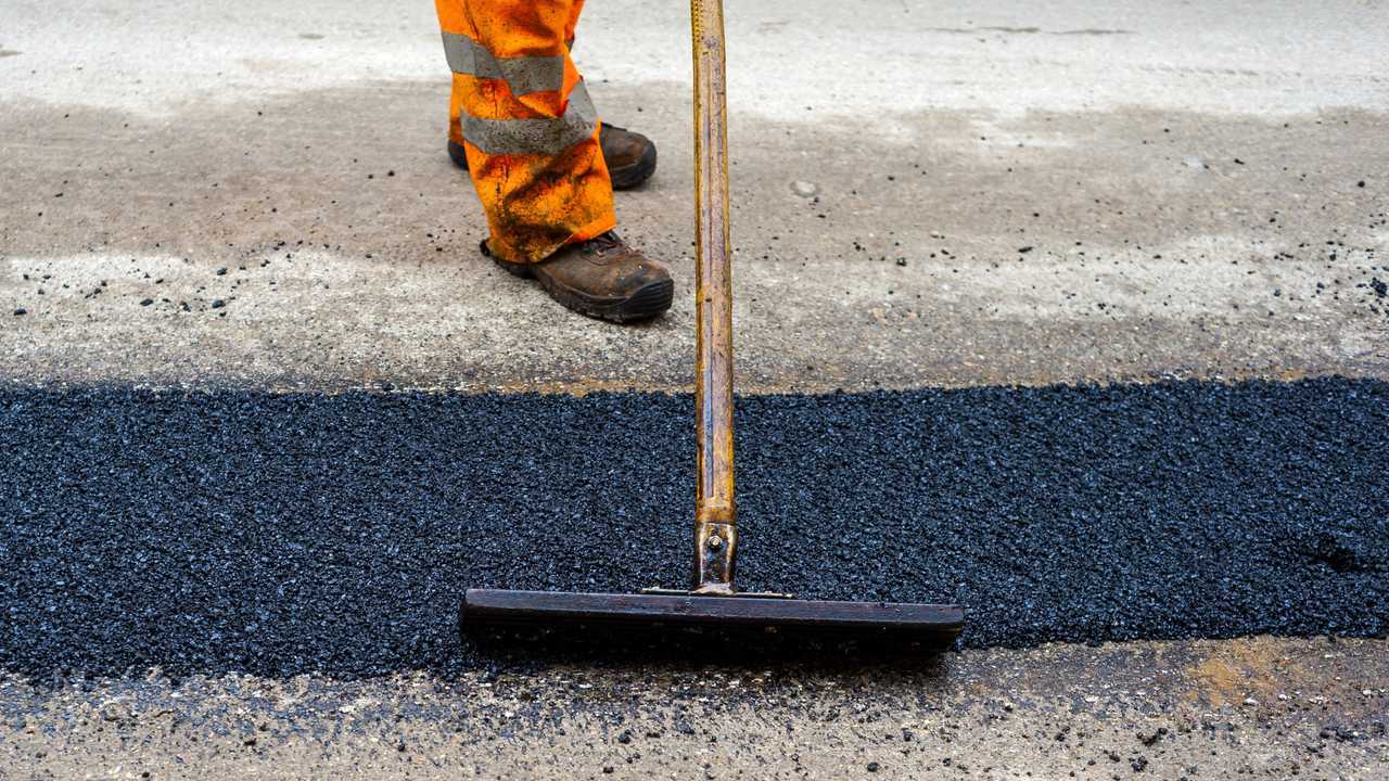 Construction worker leveling out fresh asphalt