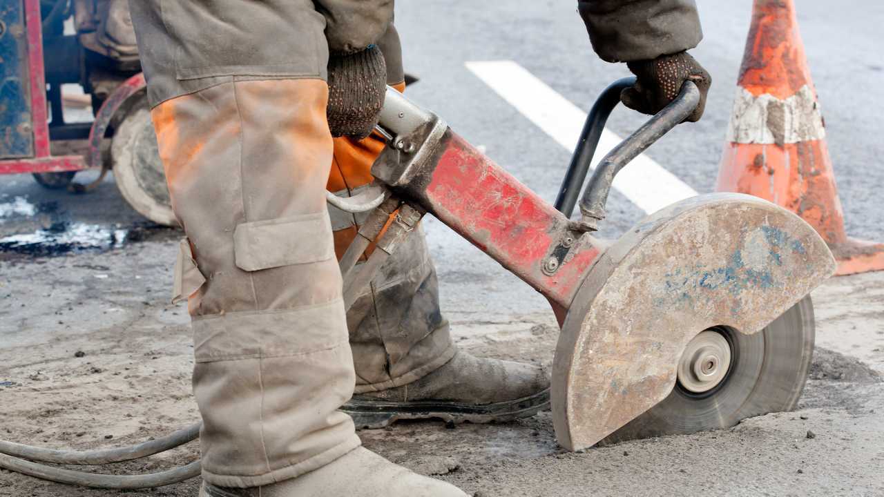 Cutting asphalt road for repair with angle grinder