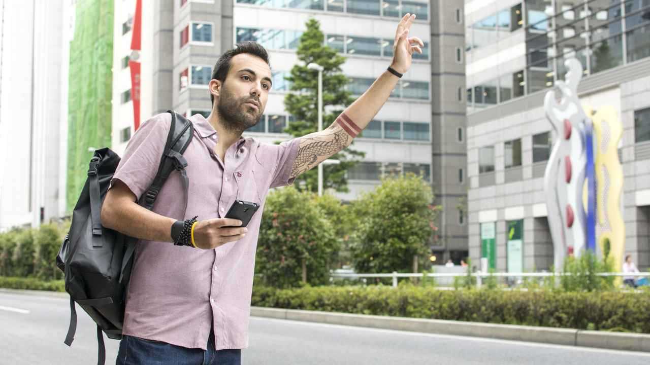 Young man hailing Uber taxi