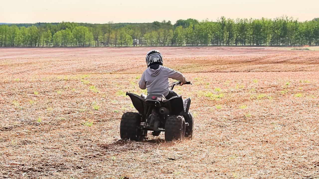Young child riding ATV quad bike in open spring field