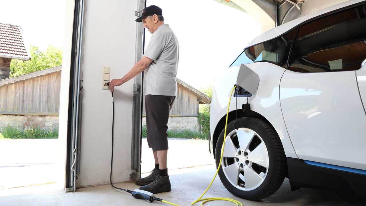 Man charging electric car at home