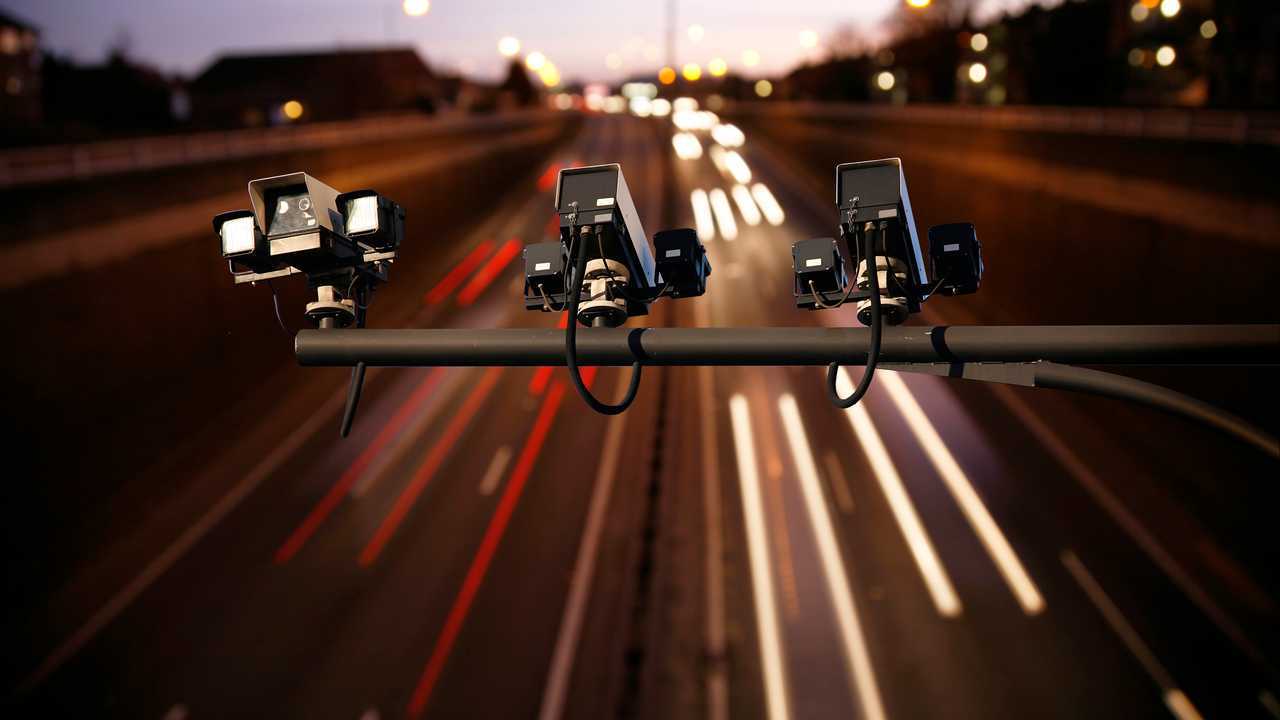 Speed camera monitoring busy traffic motorway at night
