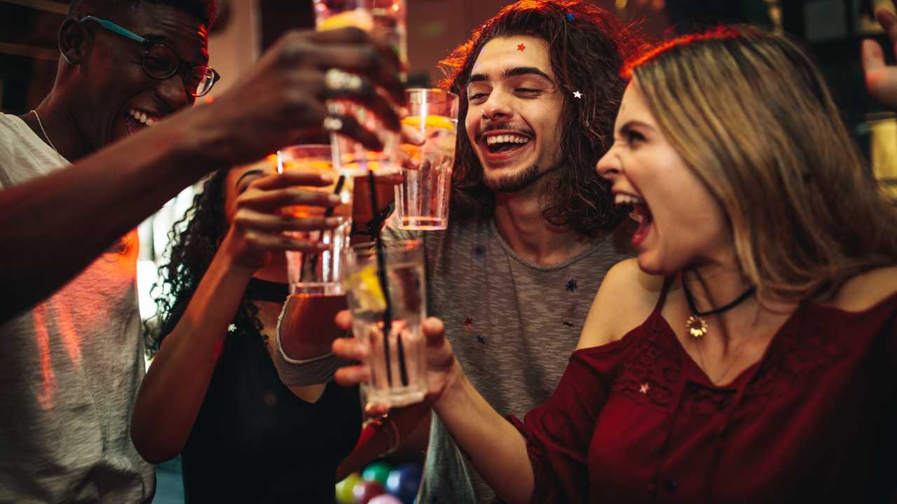 Group of friends toasting drinks and having fun at the nightclub