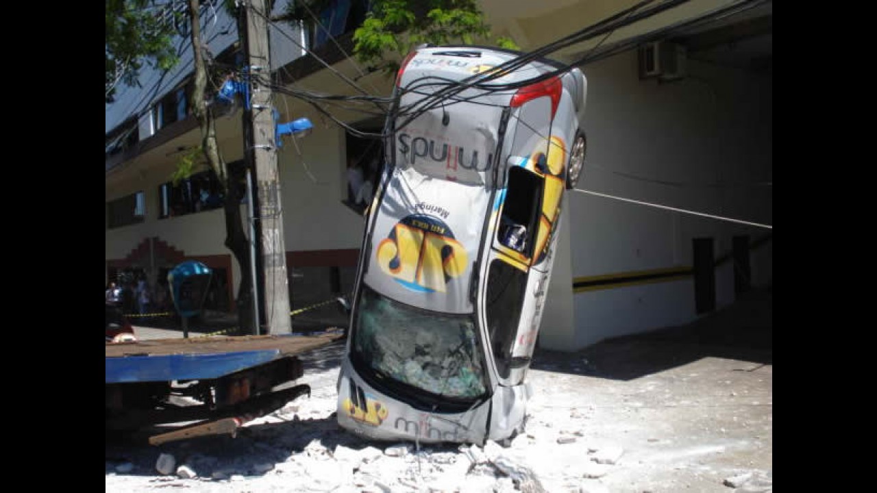 Carro cai do 3º andar de prédio e fica preso em fios de alta tensão