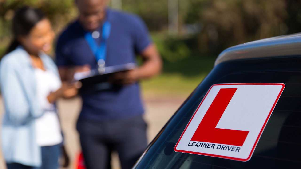 Learner driver and instructor behind a car