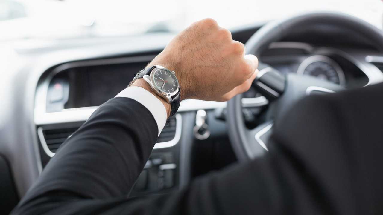 Businessman driving a car while looking at watch