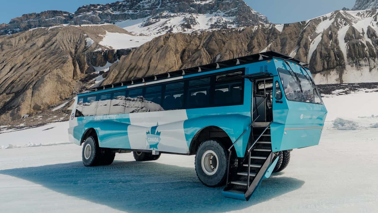 Side view of the electric Ice Explorer with mountains behind it