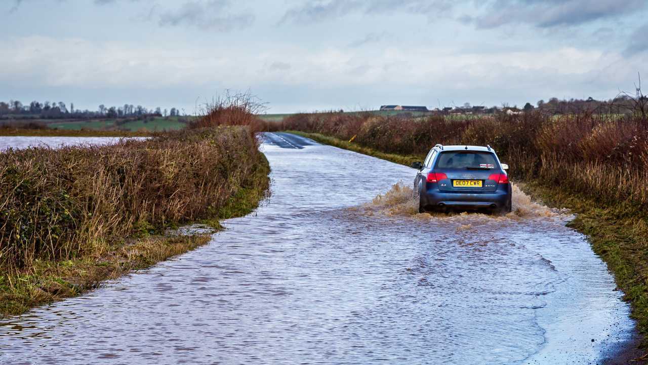Car driving through flooded road near Nunney in Somerset UK