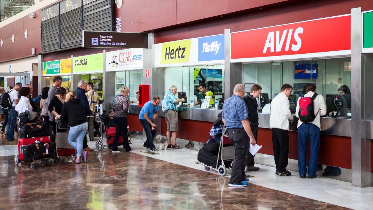 Passengers stand in queue at car rental stands at Tenerife island airport