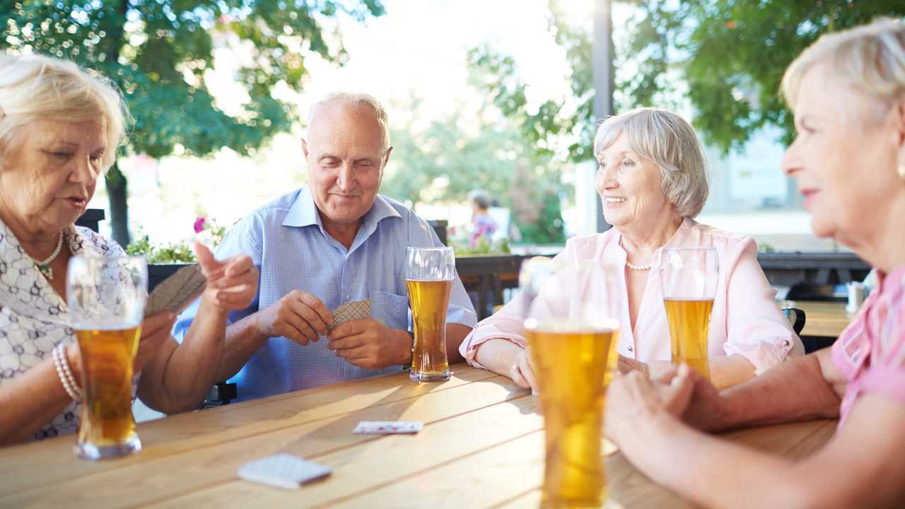 Seniors in a pub drinking beer and playing cards