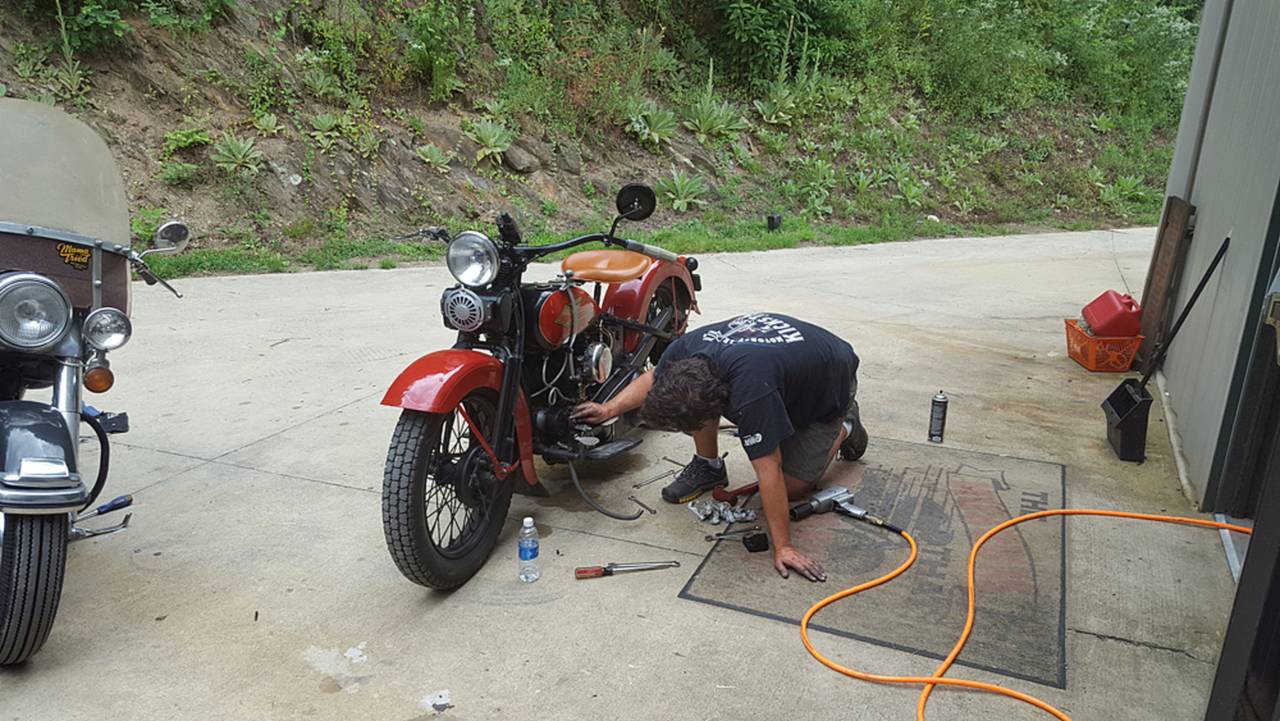 Who wants to work on their bike at home, when they can crawl around in a hot parking lot?