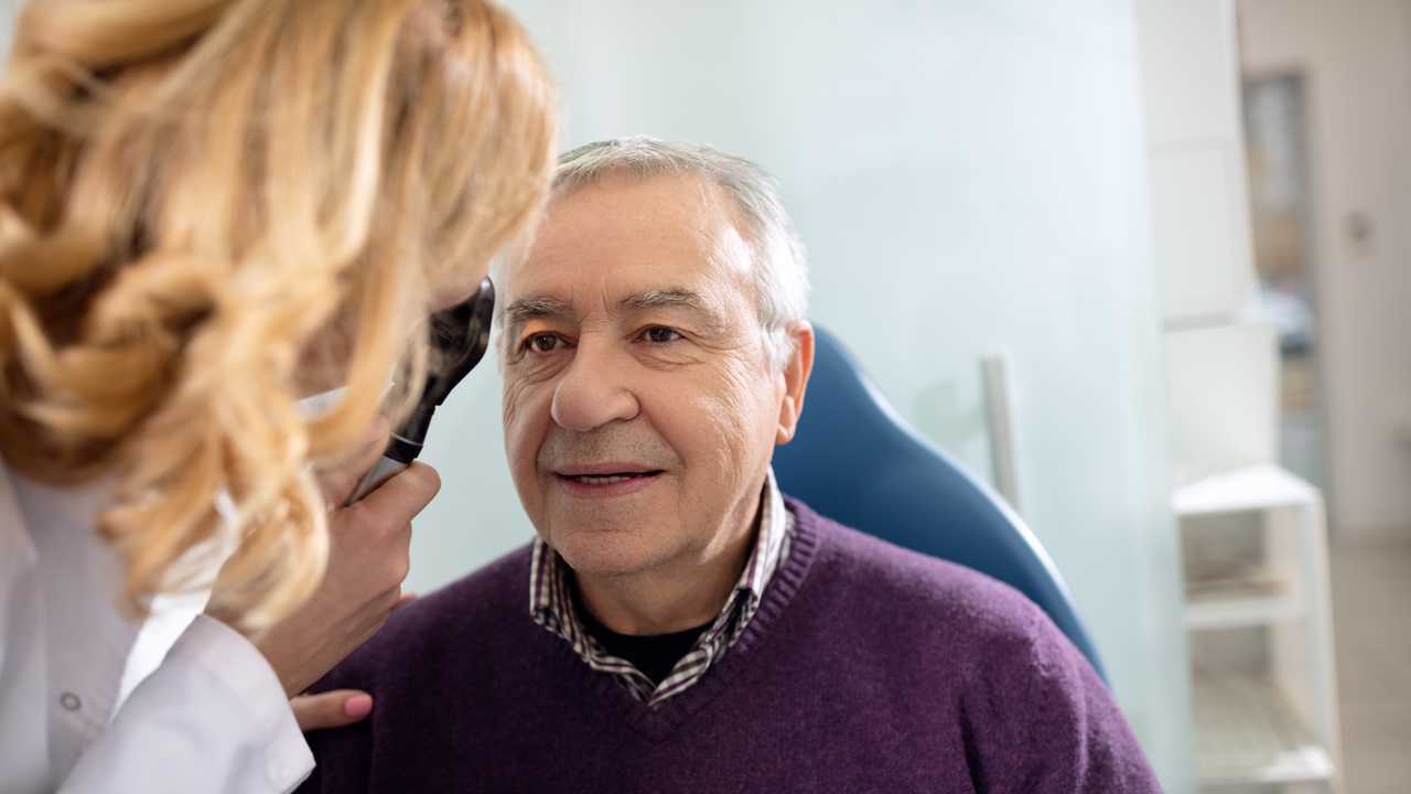 Senior looks in instrument for checking eyes at ophthalmologist