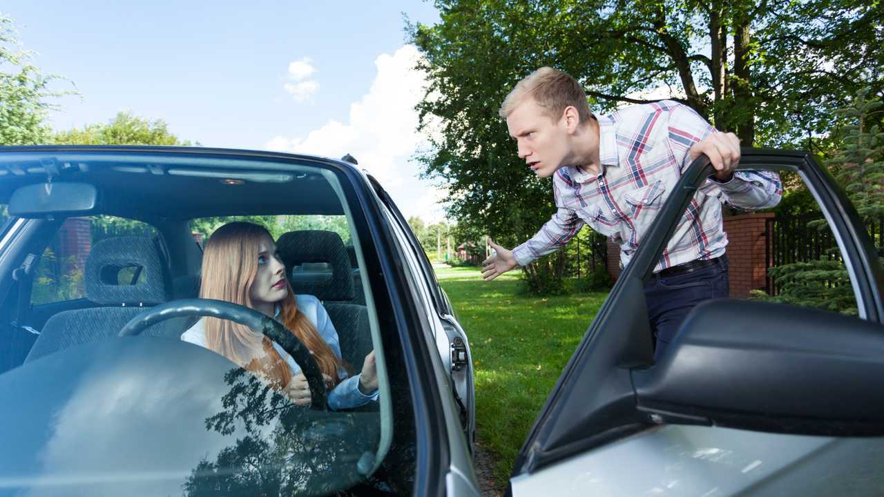 Young man mad at female driver holding door