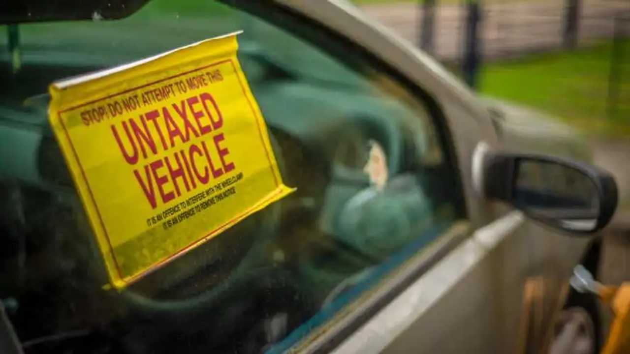 Untaxed vehicle notice on window of car with clamp on front wheel