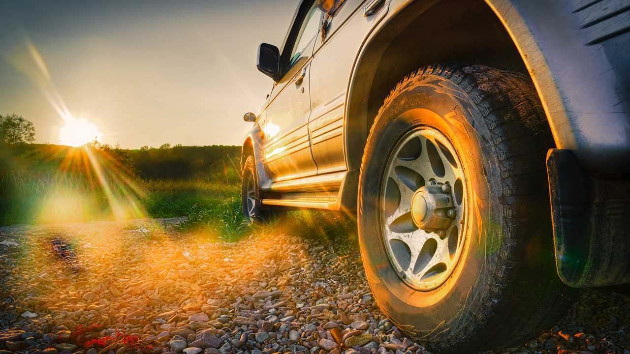 SUV driving on mountain road with beautiful sunset
