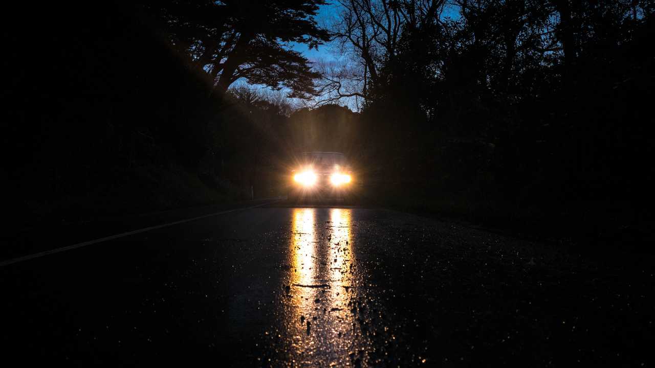 Headlights after sun down reflected in the wet road