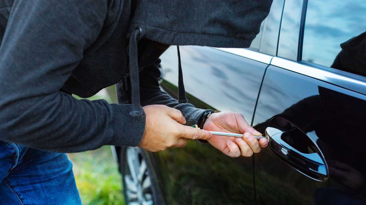 Man breaking into car door with screwdriver