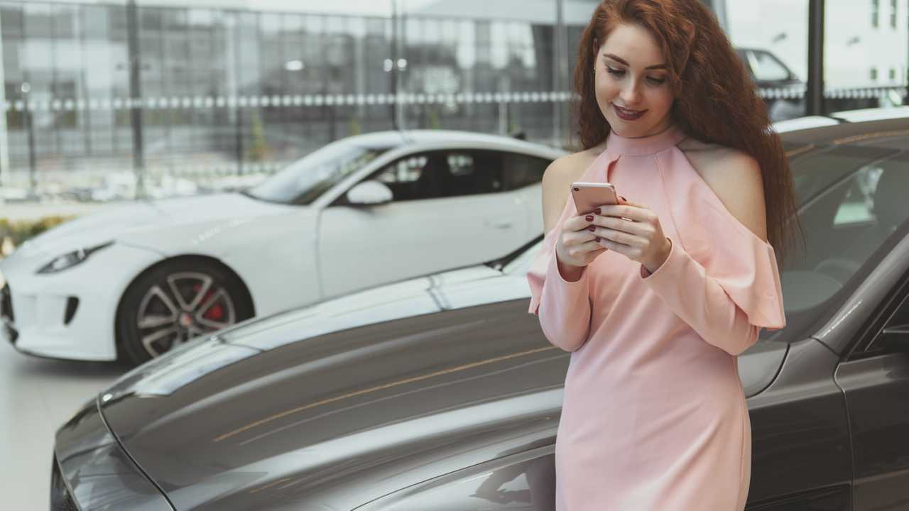 Woman on smartphone while buying car at dealership