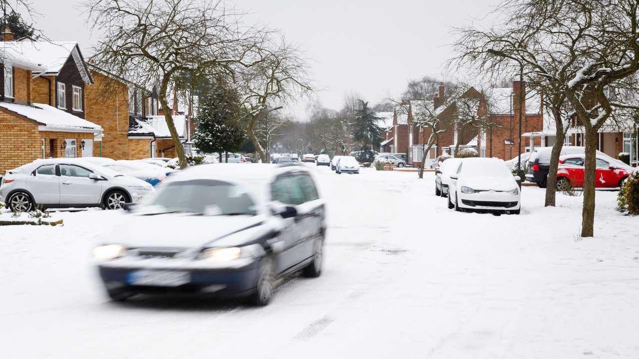 Car driving in snow covered UK residential neighbourhood