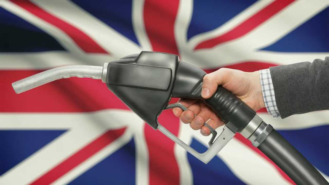 Fuel pump nozzle in hand with Union Jack flag in background