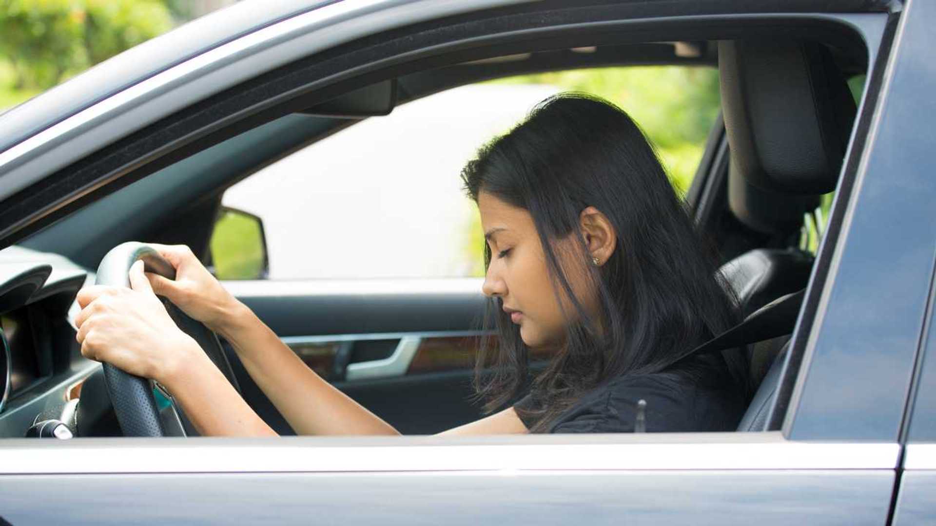 Tired woman with eyes closed while driving car | InsideEVs Photos