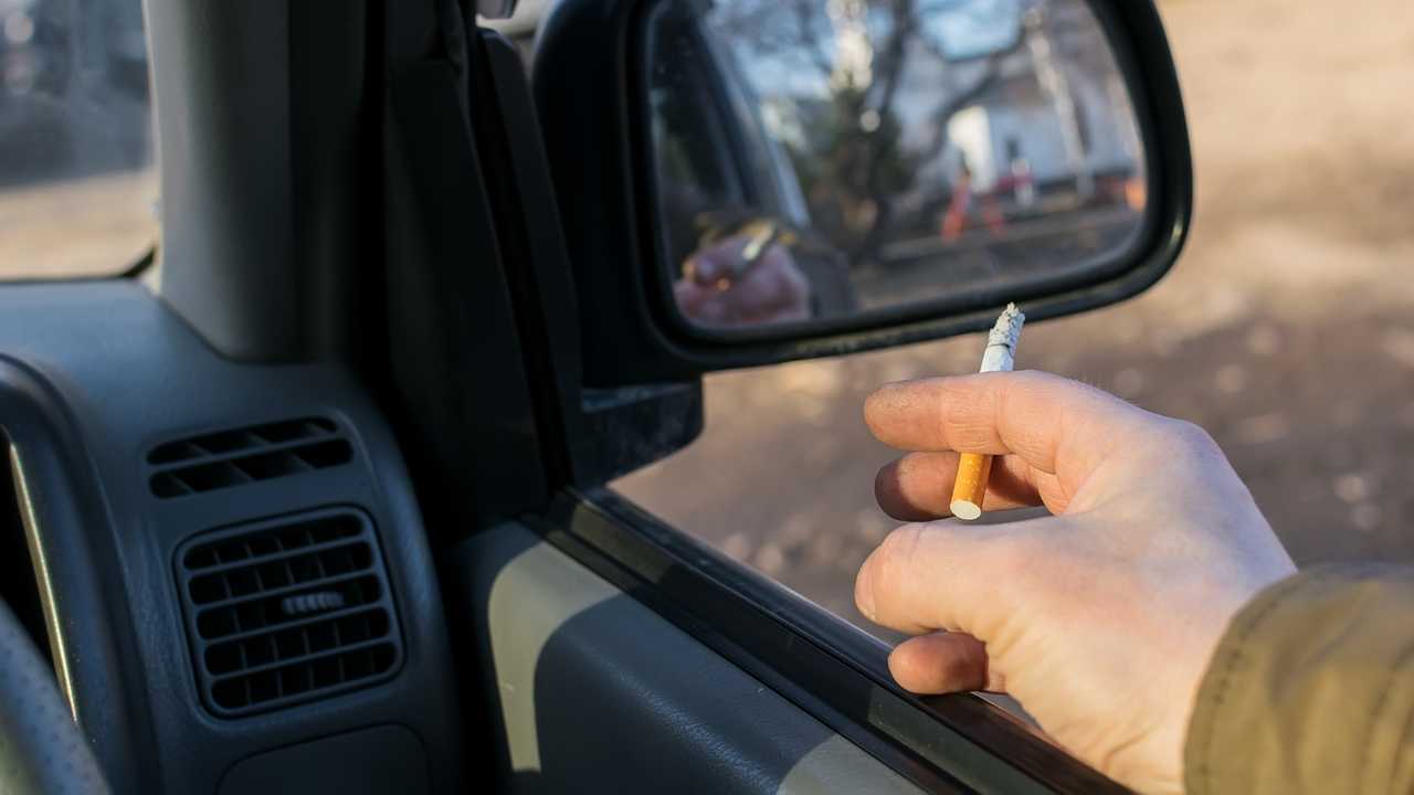 Driver smoking cigarette while sitting in parking lot