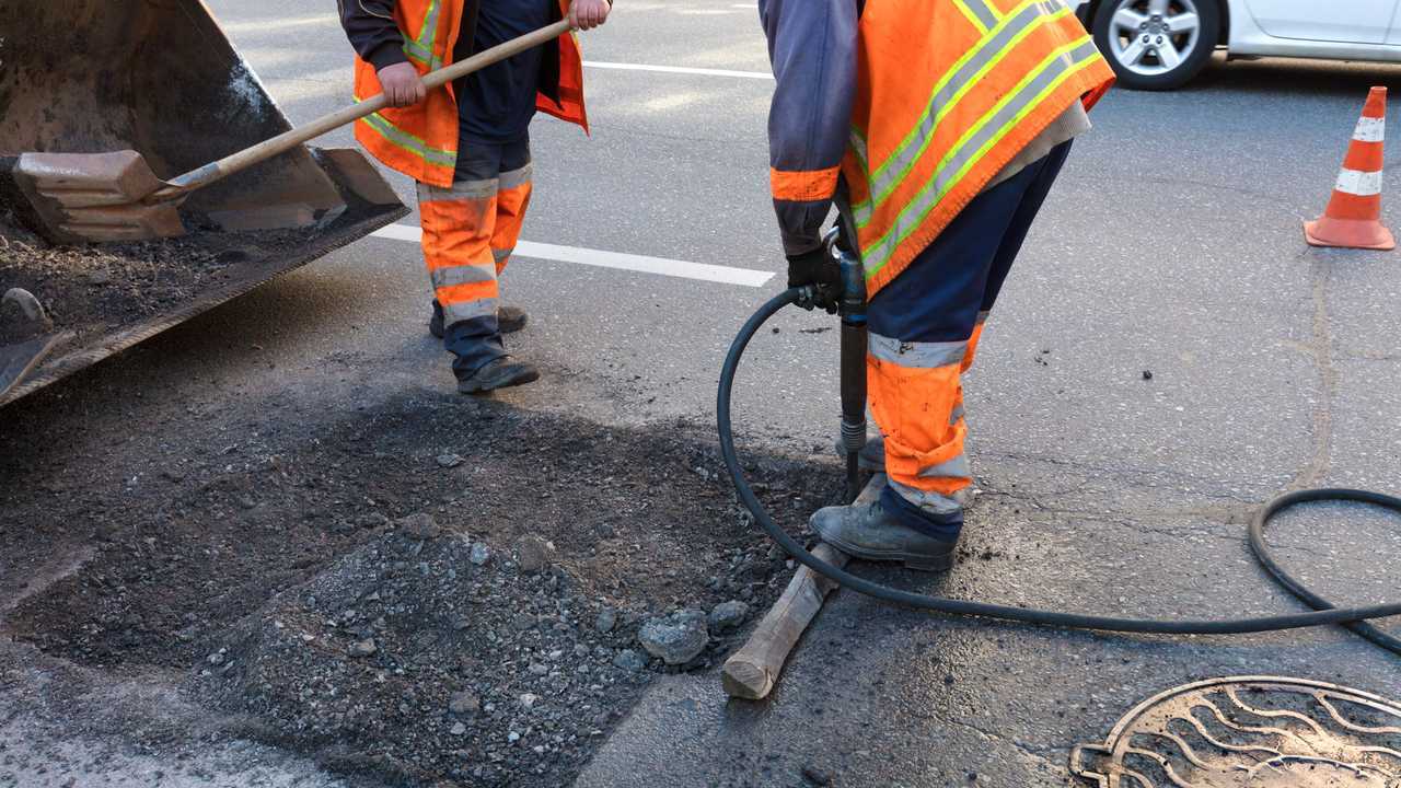 Road maintenance removes old asphalt with jackhammer