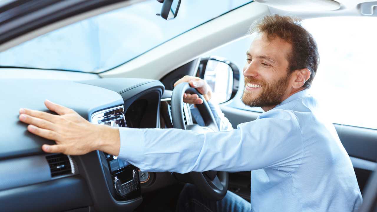 Man smiling happily sitting in his brand new car