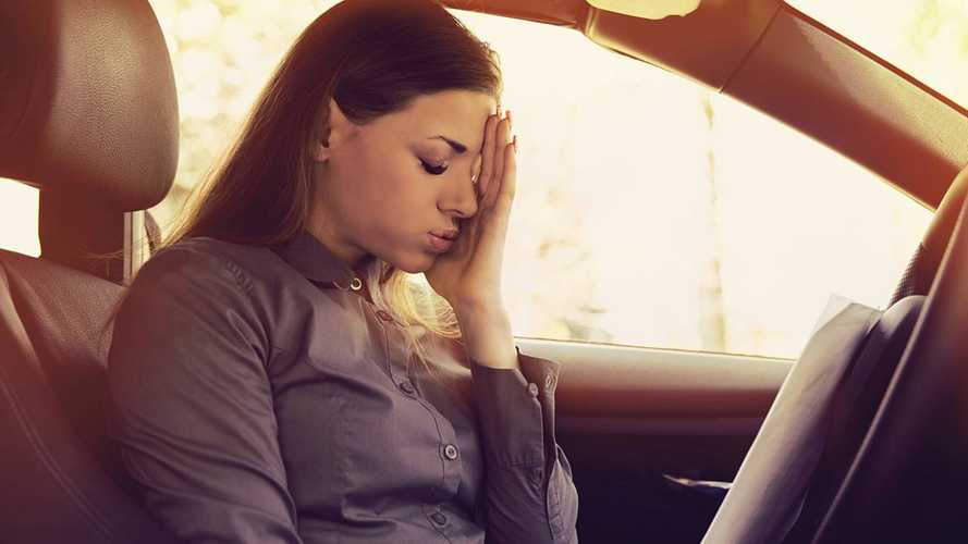 Stressed woman driver with papers sitting inside her car