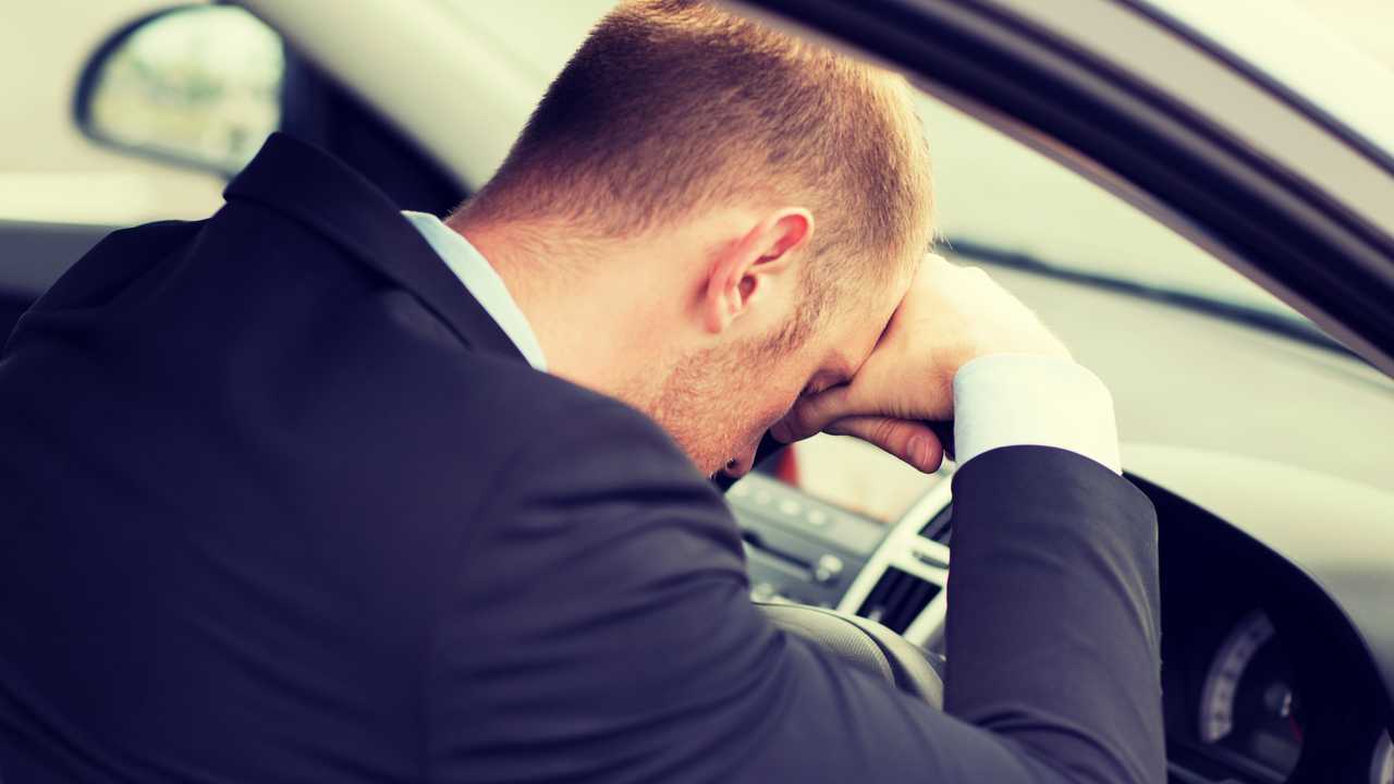 Tired businessman or taxi car driver with head on steering wheel