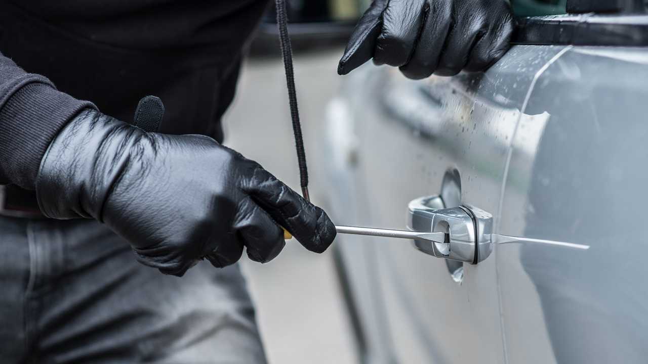 Car thief trying to break into a car with a screwdriver