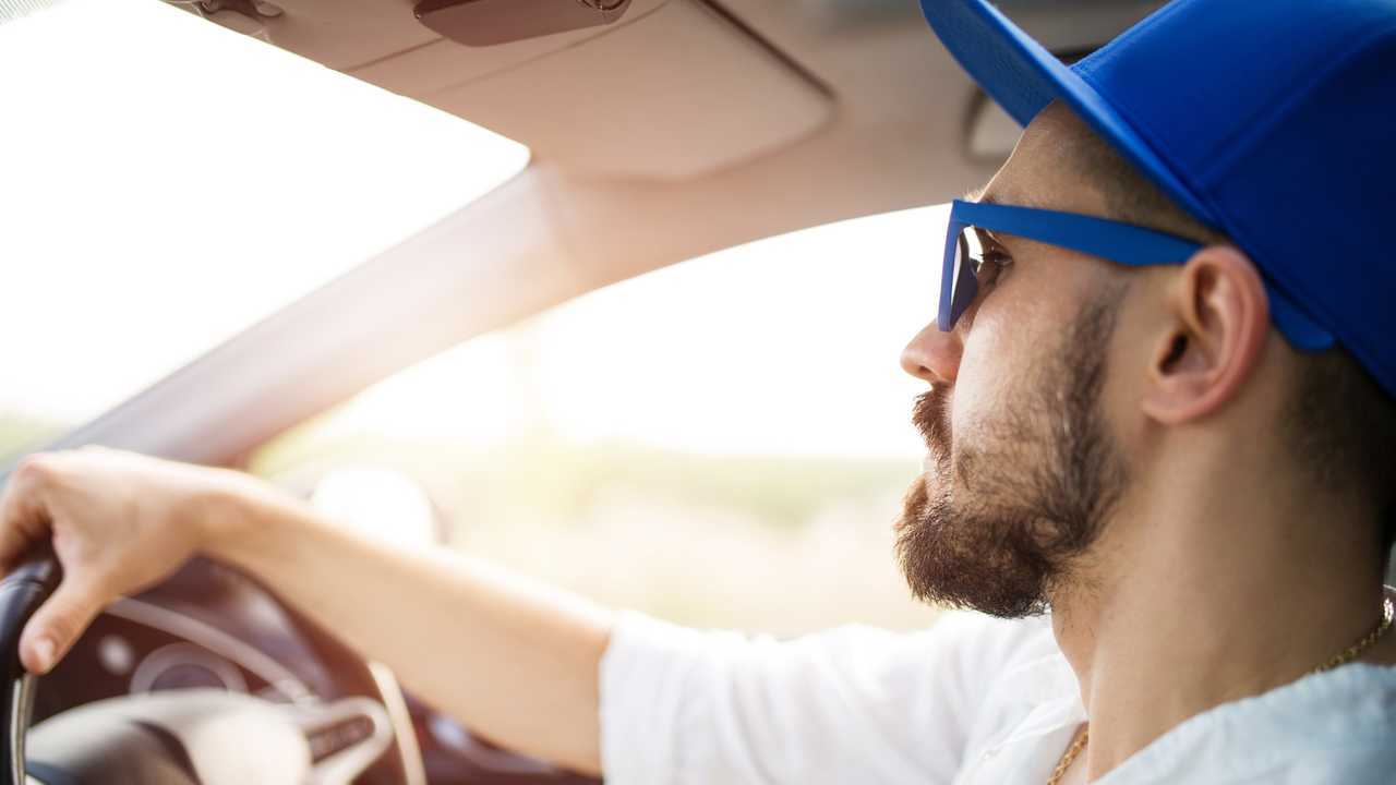 Young man driving car in sunshine