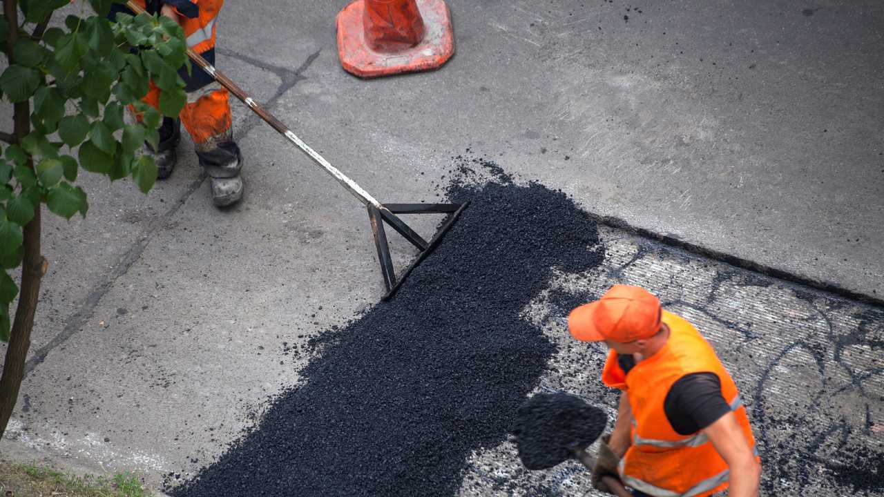 Workers resurfacing street with fresh asphalt