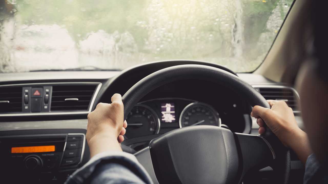 Driver gripping steering wheel tightly while driving in rain