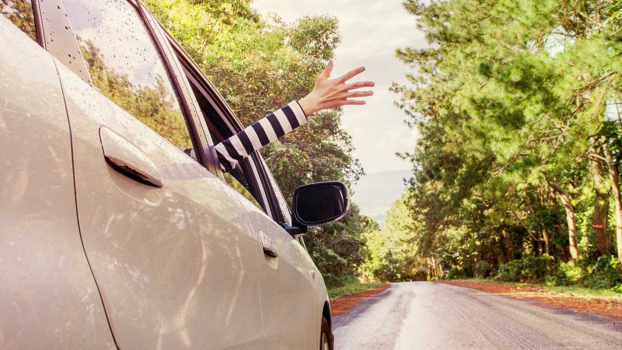 Woman enjoying car journey with hand out the window