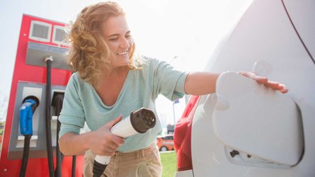 Woman at the charging station plugging in electric car