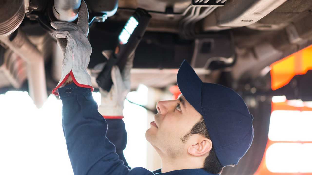 Mechanic inspecting car with torch