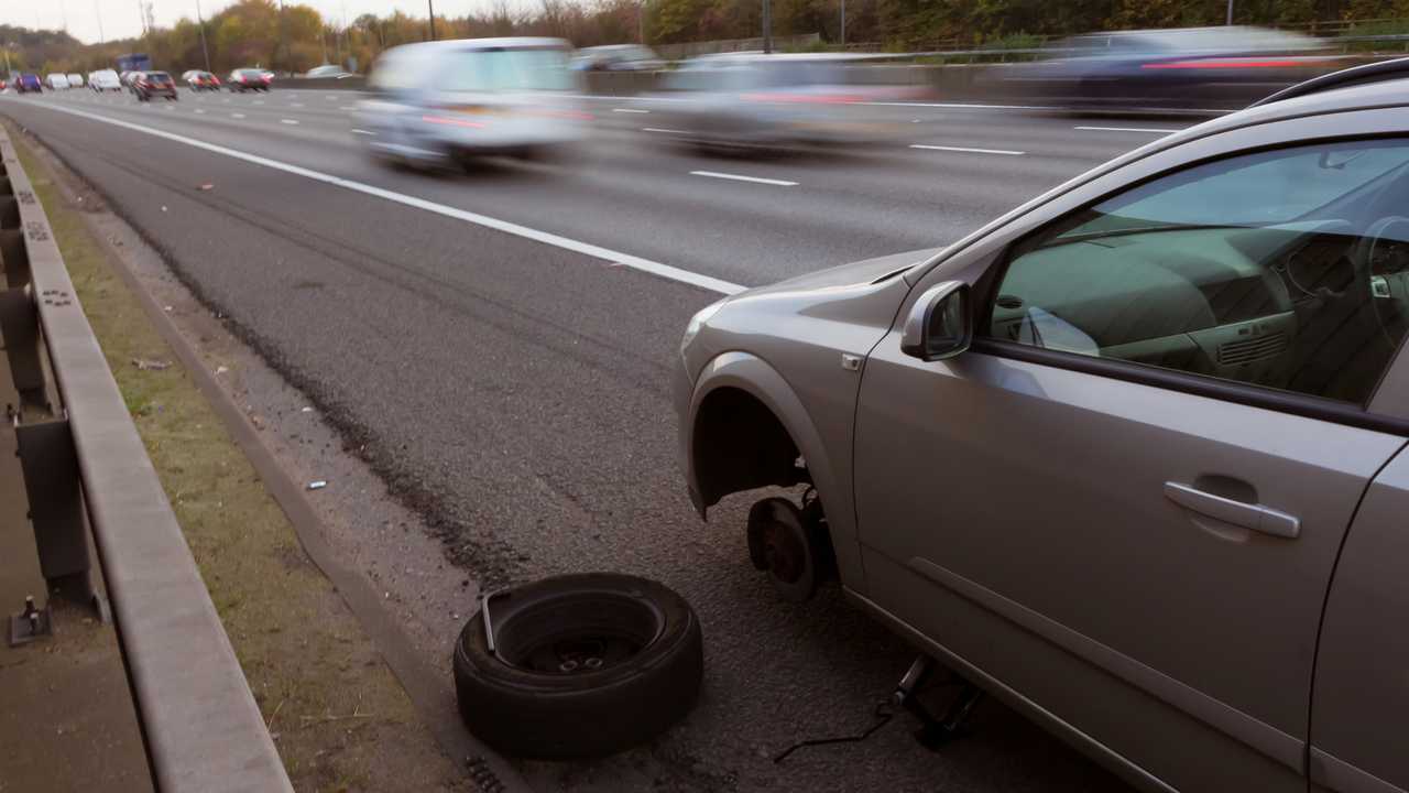 Car with flat tyre stopped on hard shoulder of motorway