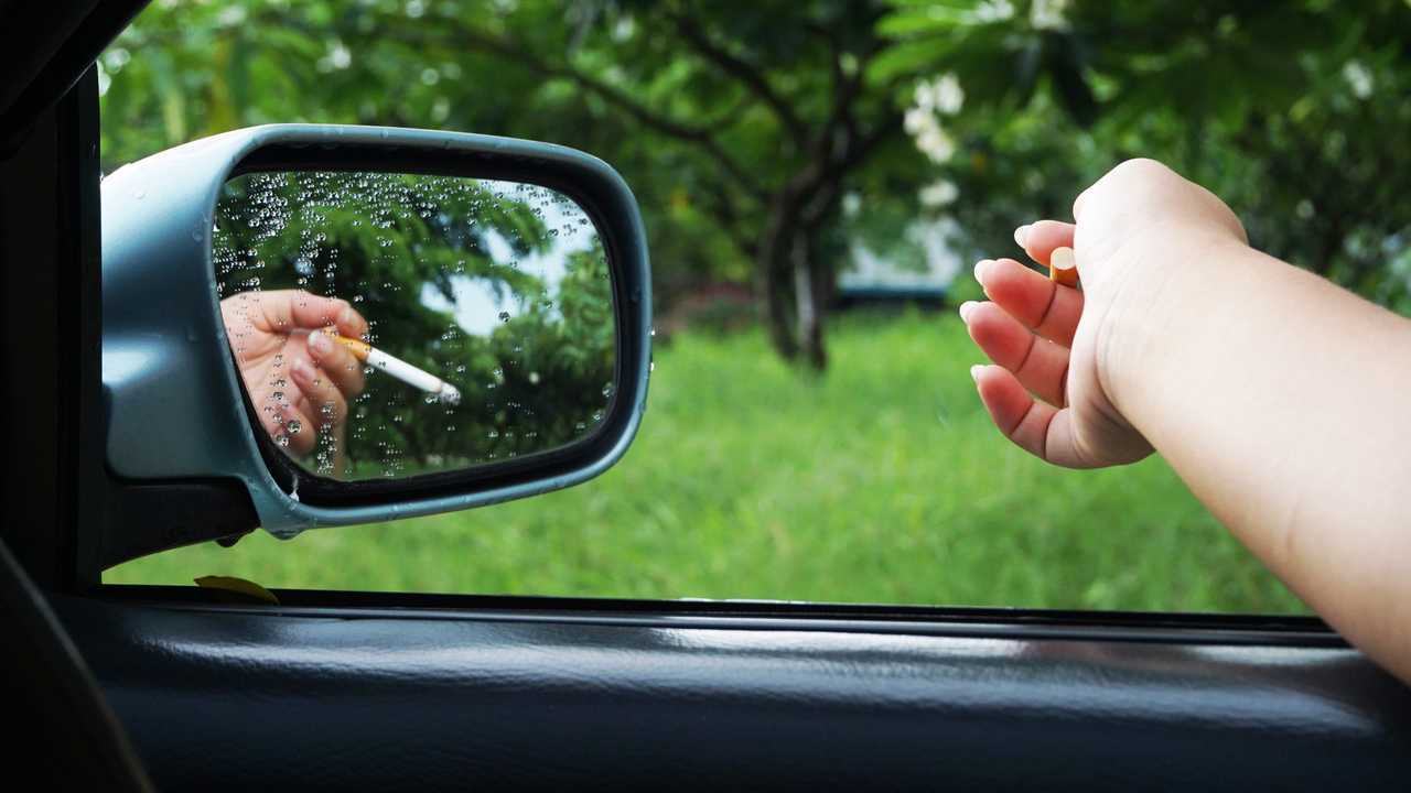 Smoker is holding cigarette out car window