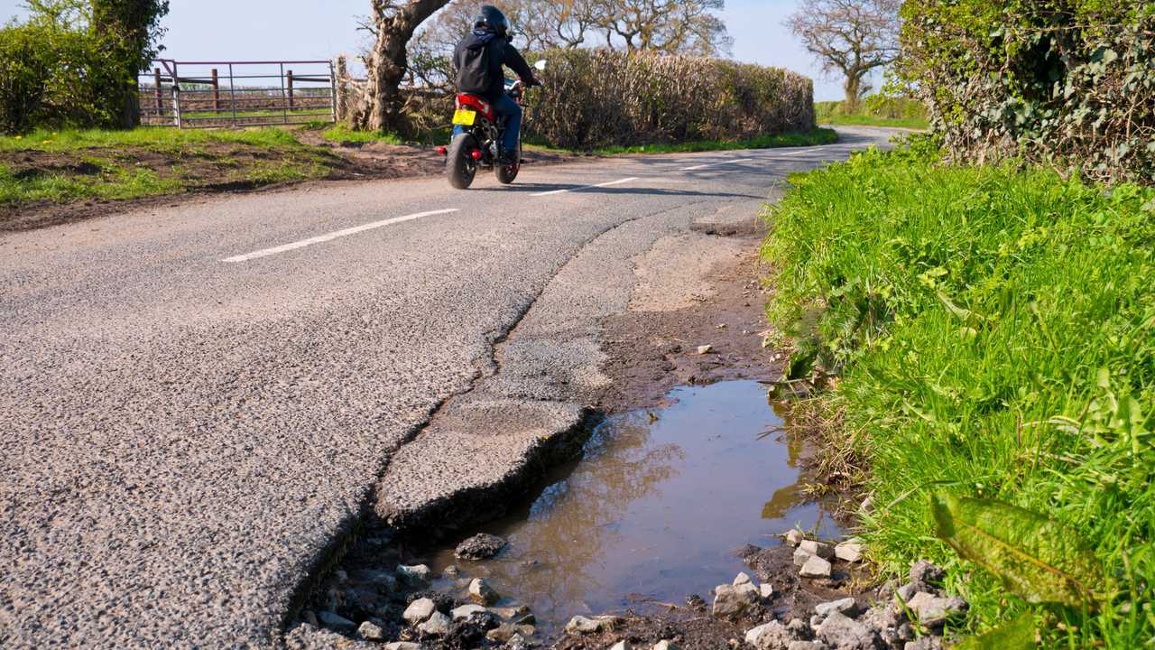 Motorcyclist passes unrepaired surface damage to road