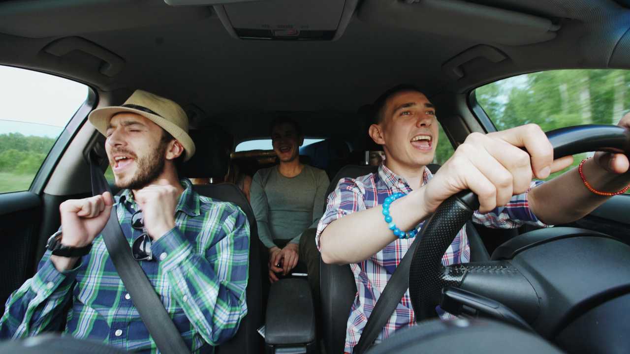 Men in car singing while driving