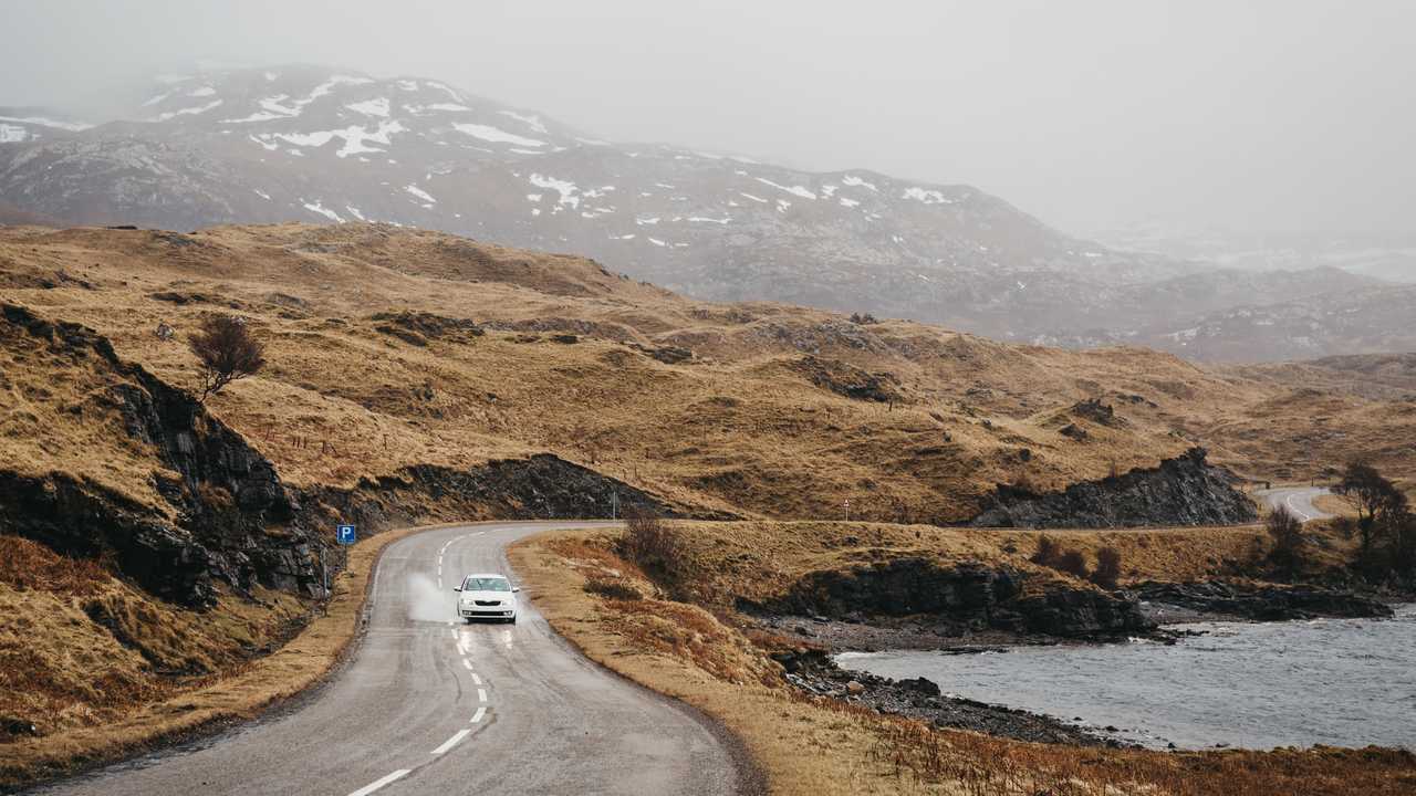 Car driving through Scottish Highlands near Lochinver on a foggy day