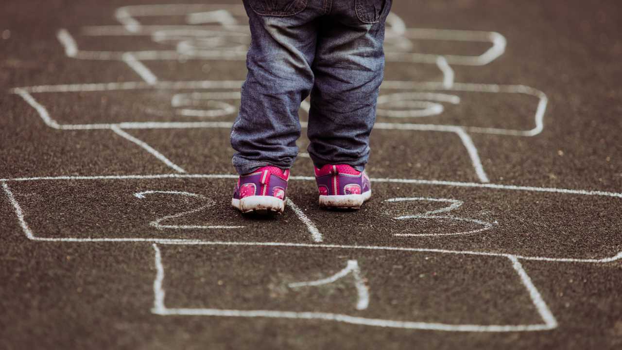 Child playing hopscotch on playground outdoors