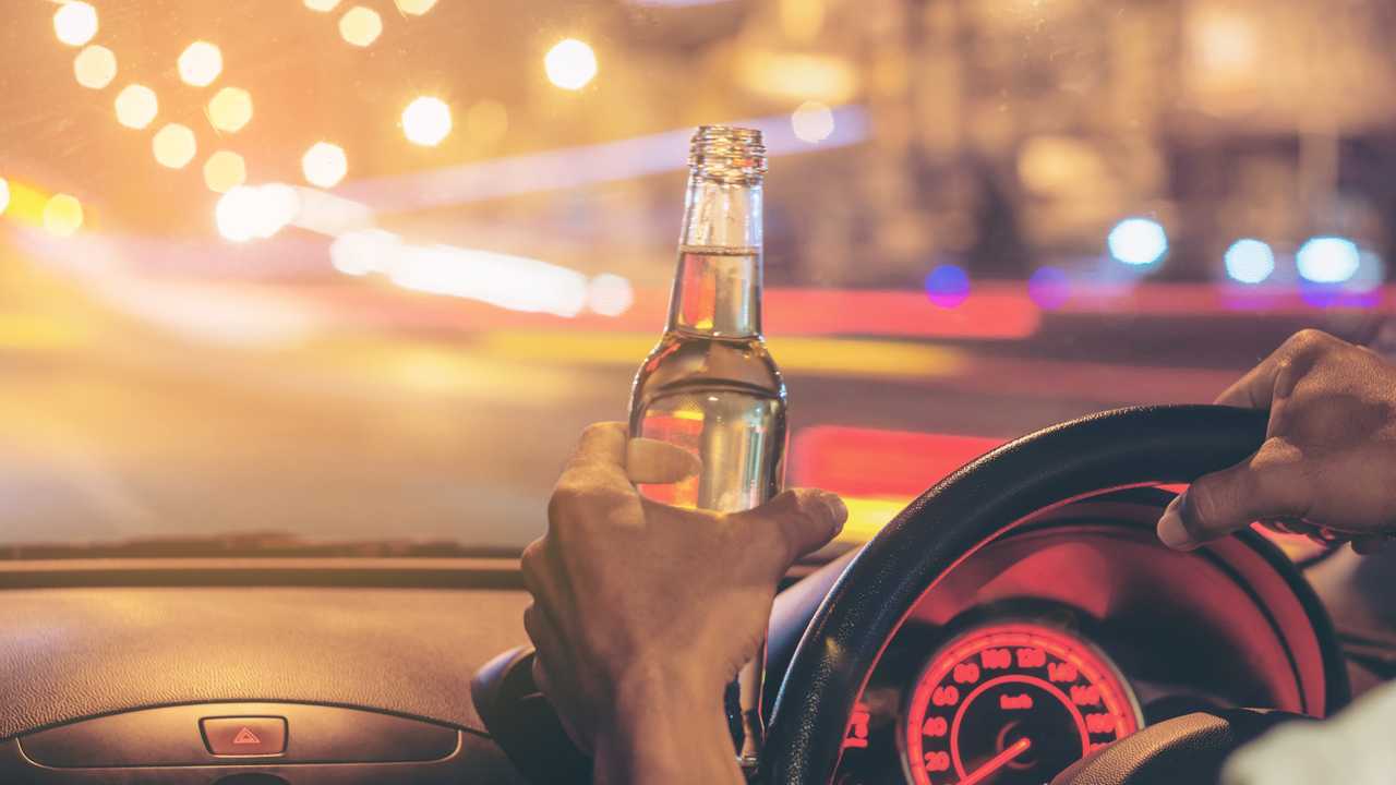 Man drives car while holding an open beer bottle