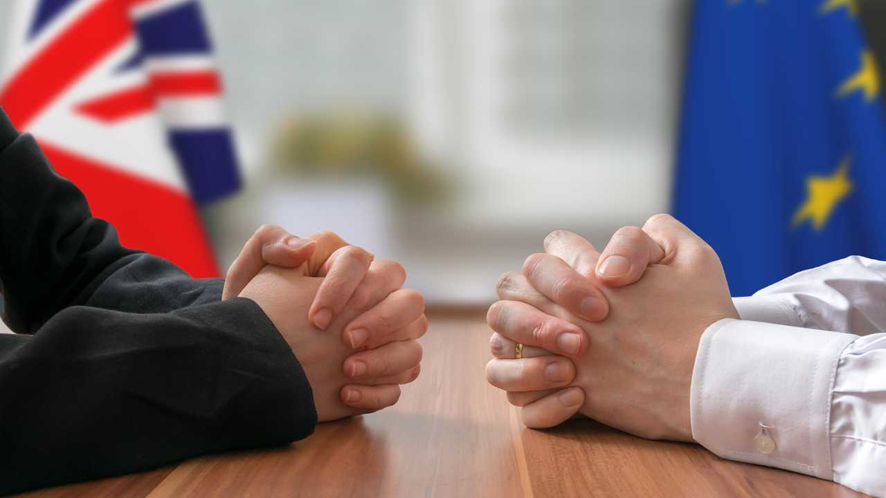 Clasped hands in mock Brexit negotiation of UK and EU politicians