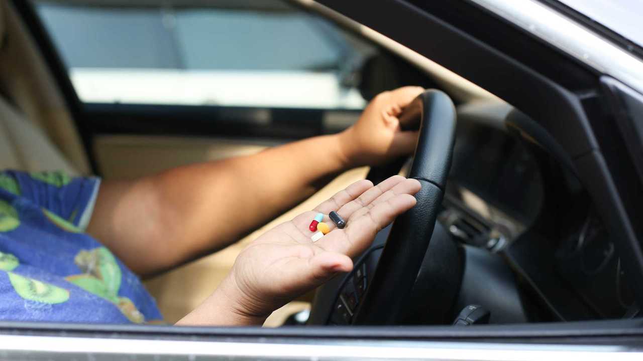 Woman holding pills inside her car while driving