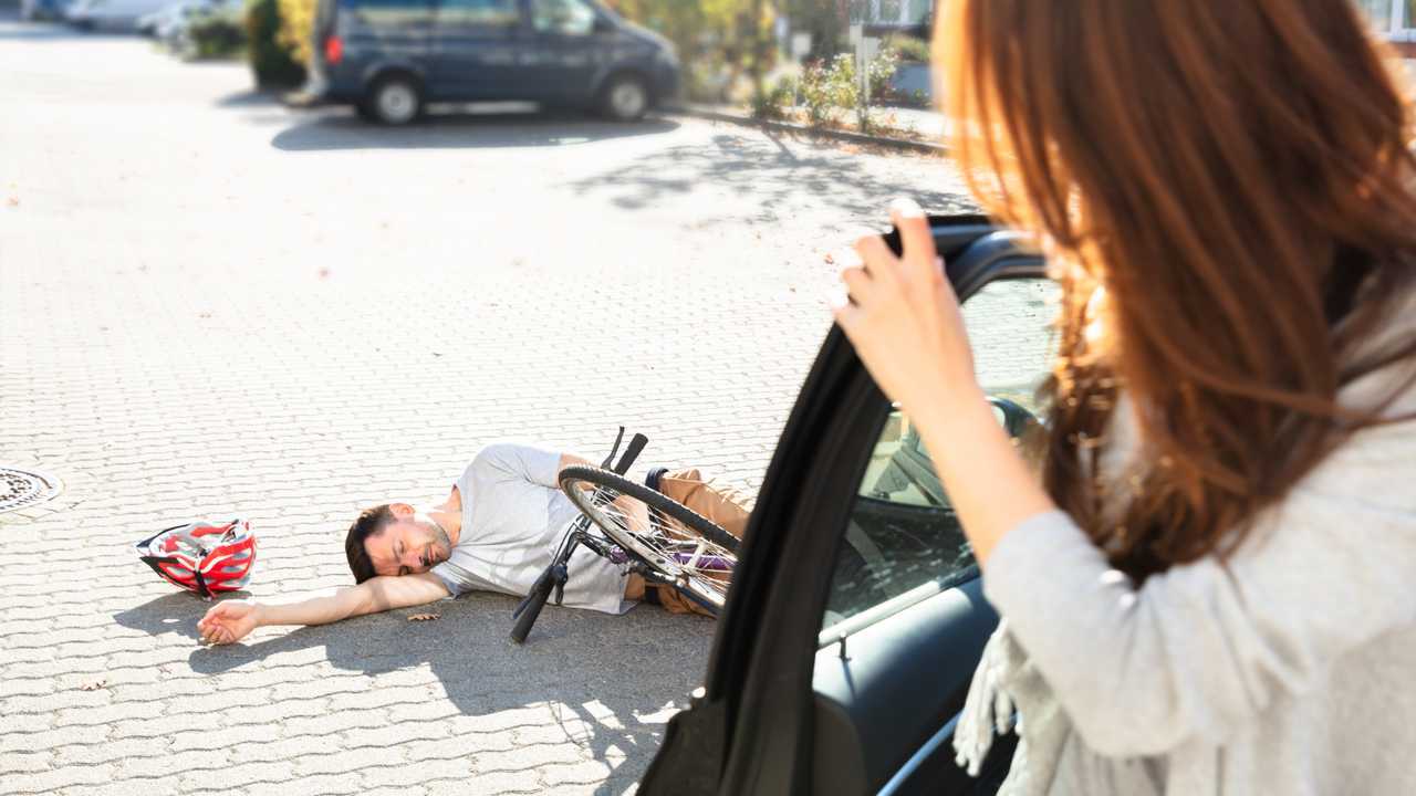 Cyclist lay in street as driver gets out of car