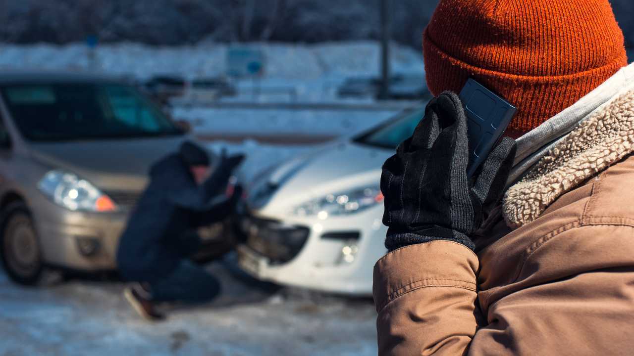 Two upset men on winter city street after car accident